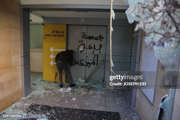 Potester sprays Arabic graffiti which reads "Depositors Outcry Association" as angry Lebanese vandalised banks in Beirut on February 16 one day after...