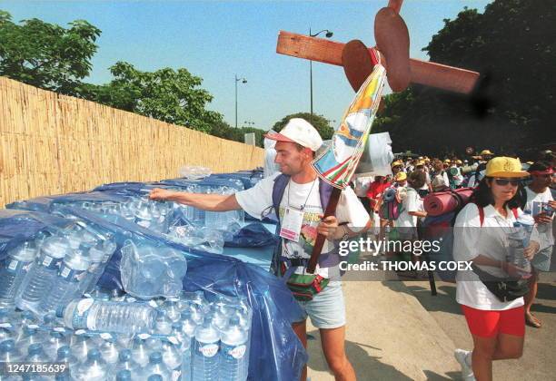 Un pèlerin prend quelques bouteilles d'eau, le 23 août, à son arrivée à Longchamp où plusieurs milliers de jeunes catholiques sont venus se...