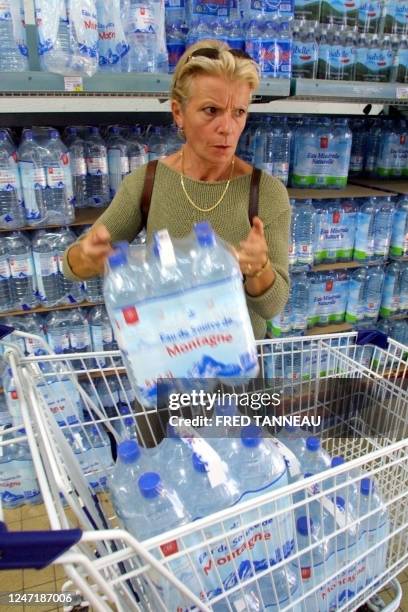 Une personne charge des packs d'eau dans un chariot le 04 septembre 2003 dans un supermarché de Pont-L'abbé, alors que l'eau du robinet, dans treize...