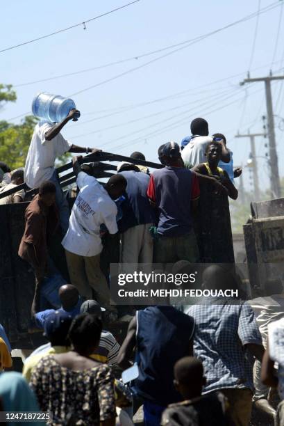 Haitians plunder a water truck 28 September 2004 in Gonaives, where tension has mounted after floods killed more than 1,100 people and residents...