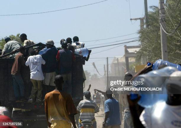Haitians plunder a water truck 28 September 2004 in Gonaives, where tension has mounted after floods killed more than 1,100 people and residents...