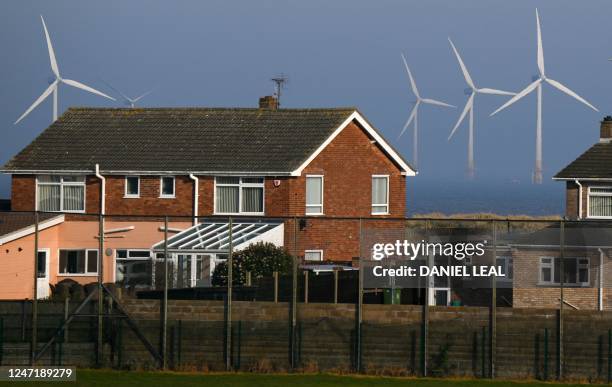 Wind turbines at RWE's Scroby Sands Wind Farm, are pictured on th horizon beyond residential houses, in Great Yarmouth, eastern England, on February...
