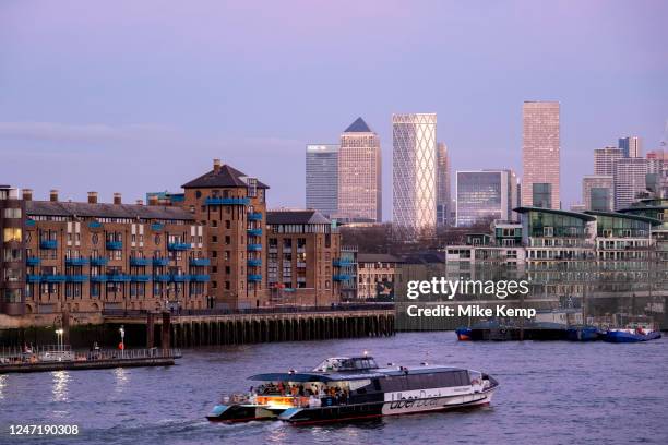 Boats and barges on the River Thames overlooking Wapping with Canary Wharf business district beyond on 5th Febuary 2023 in London, United Kingdom....