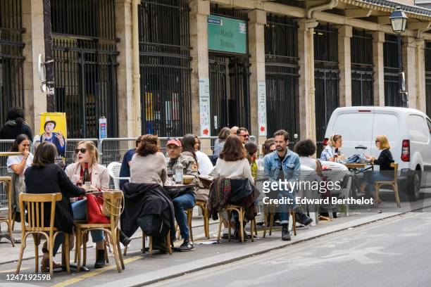 People sit at a terrace on the street between parking spaces, as bars and restaurants reopen after two months of nationwide restrictions due to the...