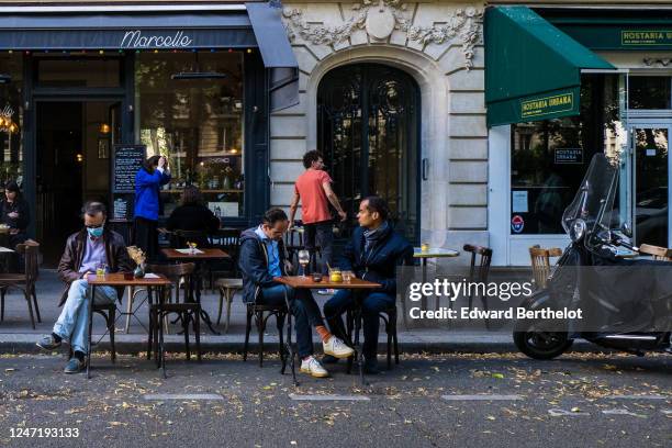 People sit at a terrace on the street between parking spaces, as bars and restaurants reopen after two months of nationwide restrictions due to the...