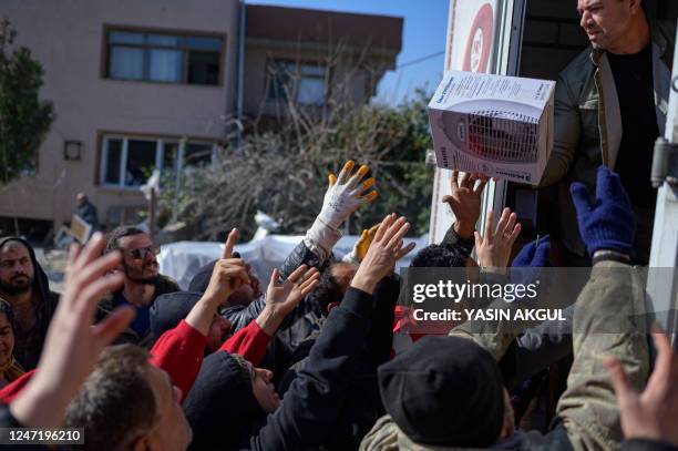 Residents grab food, clothes and household items delivered from the back of a truck in Samandag, south of Hatay on February 16 ten days after a...