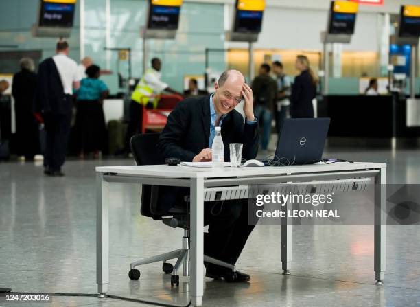 Author Alain de Botton writes at his desk in the check-in area during his week as writer-in-residence at Heathrow Airport, west London, on August 20,...