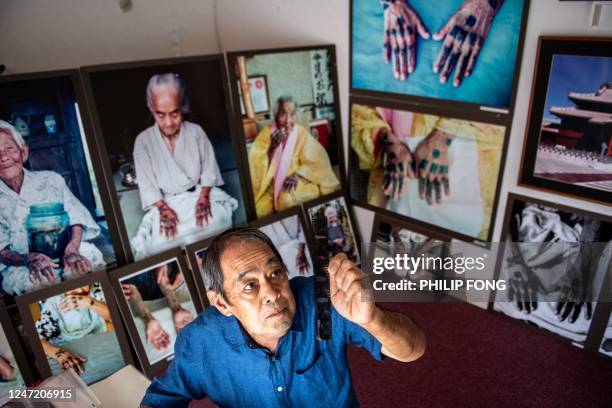 This picture taken on August 23, 2022 shows veteran photographer Hiroaki Yamashiro checking archived negative and transparency films at his studio...