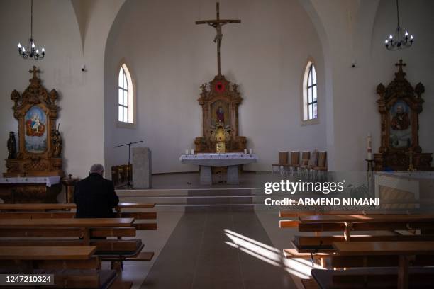 Ismet Sopi prays in the church of the village of Llapushnik on February 2, 2023. - In an austere church perched above a picturesque valley in central...