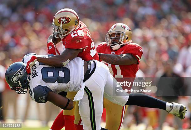 Anthony McCoy of the Seattle Seahawks is hit by Madieu Williams and Donte Whitner of the San Francisco 49ers during their season opener at...