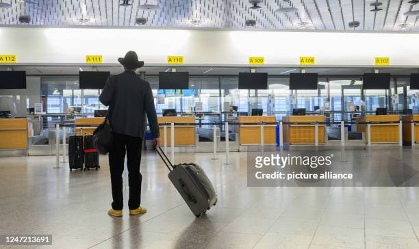 February 2023, Lower Saxony, Hanover: A passenger stands in front of empty check-in counters in Terminal A at Hanover Airport. The trade union Verdi...