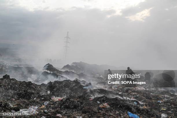 Waste pickers collect things amidst heavy smoke from burning garbage, mostly plastic and textiles, at the Gioto Dumping site.