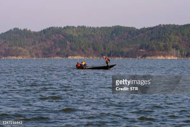 This photo taken on February 15, 2023 shows researchers releasing a finless porpoise into Poyang Lake after giving it a physical examination in...