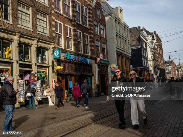 Tourists are seen walking and going shopping in the city center. Amsterdam is one of the most beautiful, creative, and cycle-friendly cities in...