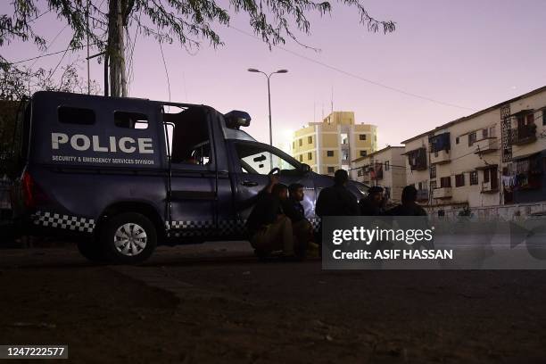 Security personnel take position behind a police vehicle near site of an attack to a police compound in Karachi on February 17, 2023. - A gunbattle...