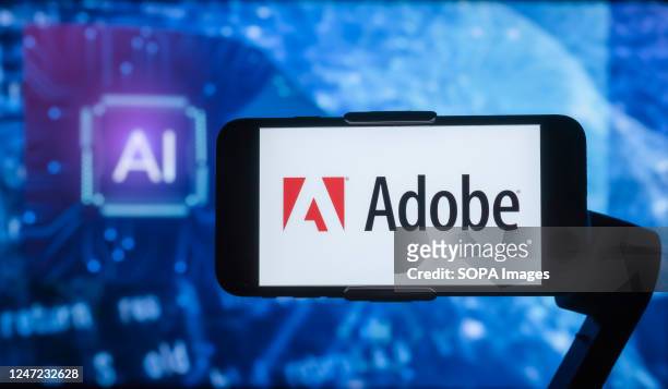 In this photo illustration, the logo of Adobe is seen displayed on a mobile phone screen with AI written in the background.