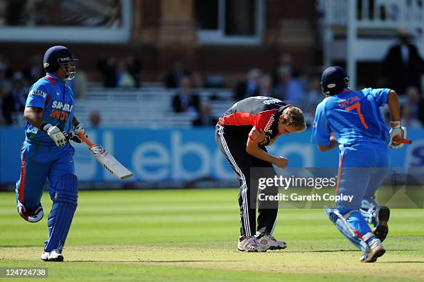 Stuart Broad of England holds his right arm as MS Dhoni and Suresh Raina of India run between the wickets during the 4th Natwest One Day...