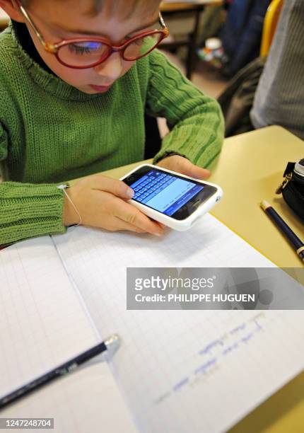 Twitter à l'école, un moyen efficace pour apprendre à lire et à écrire" - Un élève de CE1 écrit un message sur un téléphone portable lors d'une leçon...
