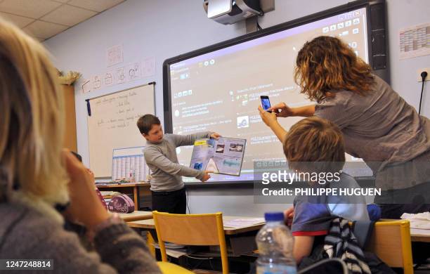 Twitter à l'école, un moyen efficace pour apprendre à lire et à écrire" - Céline Lamare, institutrice, prend une photo avec un téléphone portable...