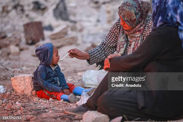 Syrian woman feeds his baby amid collapsed buildings as Syrians continue their lives in harsh conditions in quake hit Jindires district of Aleppo,...