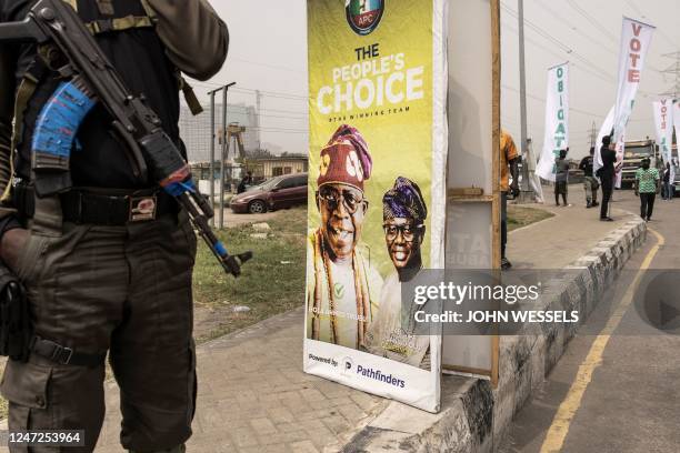 Private security stands next to an election poster for All Progressive Congress leader, Bola Tinubu in Lagos on February 18 ahead of the Nigerian...