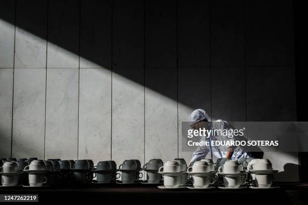 Cleaning lady stands behind a table with coffee cups before the opening ceremony of during the 36th Ordinary Session of the Assembly of the African...