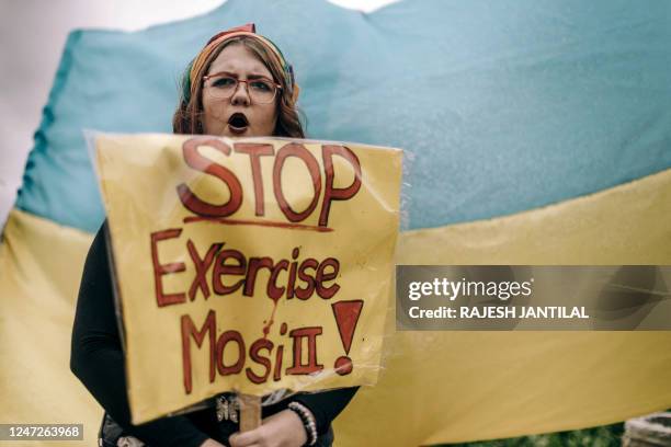 Protester holds a slogan in front of a Ukraine's flag during a demonstration at Umhlanga beach in Durban on February 18 against South Africa's joint...