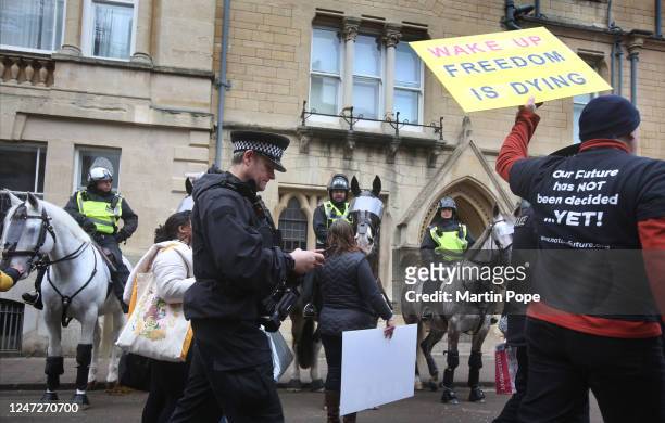 Protester holds a sign saying Wake Up Freedom is Dying as he walks past police officers on horseback on February 18, 2023 in Oxford, England. The...