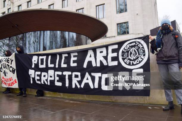 Protesters hold a banner which states 'Police are perpetrators' during the demonstration outside New Scotland Yard. Protesters gathered outside New...
