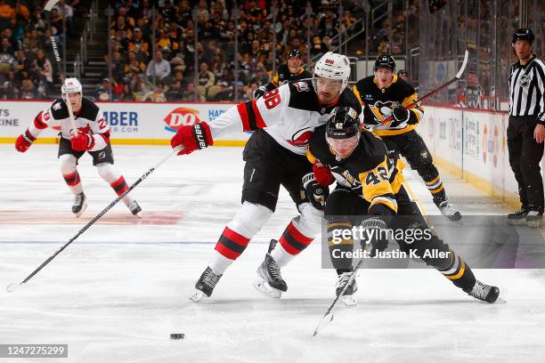 Kasperi Kapanen of the Pittsburgh Penguins and Kevin Bahl of the New Jersey Devils battle at PPG PAINTS Arena on February 18, 2023 in Pittsburgh,...
