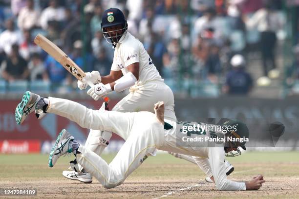 Peter Handscomb of Australia dives to stop the ball as Cheteshwar Pujara of India looks on during day three of the Second Test match in the series...