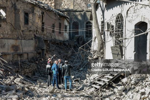 People inspect damage in the aftermath of an Israeli air strike that hit the medieval Citadel of Damascus on February 19, 2023. - The air strike on...