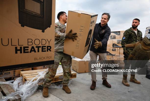 Secretary of State Antony Blinken helps US military personnel to load aid onto a vehicle, at Incirlik Air Base near Adana, on February 19 during an...