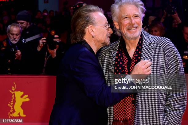 Irish singer and U2 frontman Bono and Irish musician and U2 bassist Adam Clayton pose on the red carpet prior to the premiere of the film 'Kiss the...