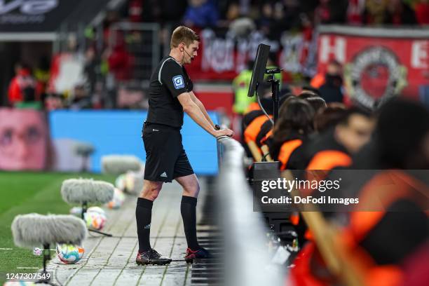 Referee Robert Schroeder looks at VAR during the Bundesliga match between Bayer 04 Leverkusen and 1. FSV Mainz 05 at BayArena on February 19, 2023 in...