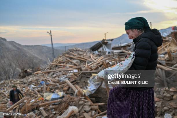 This photograph taken on February 19 shows a woman crying as she collects her personal belongings atop the rubble of her collapsed house in...