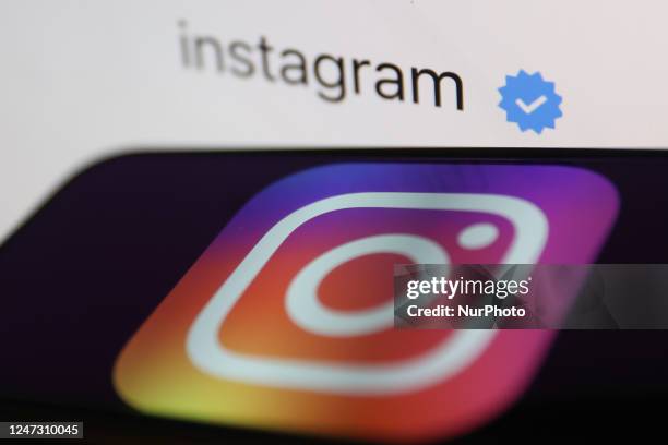 Blue verification checkmark on Instagram account on Instagram displayed on a laptop screen and Instagram logo displayed on a phone screen are seen in...