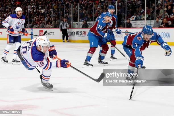 Zach Hyman of the Edmonton Oilers takes a shot while Devon Toews the Colorado Avalanche defends at Ball Arena on February 19, 2023 in Denver,...