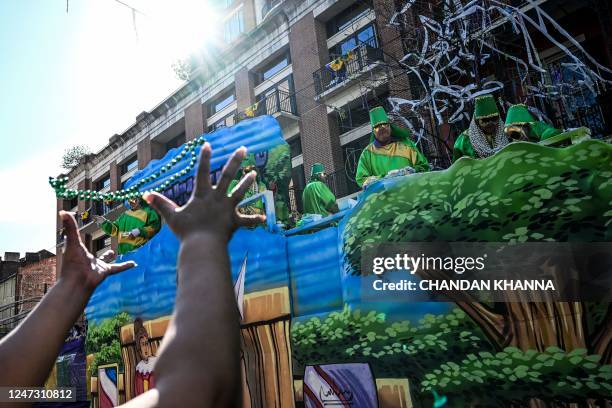 Revellers catch beads from a float in the 2023 Krewe of Okeanos parade during Mardi Gras in New Orleans, Louisiana, on February 19, 2022.