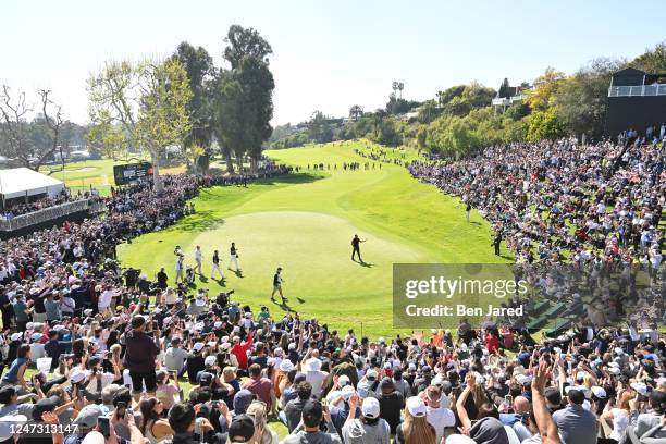 Tiger Woods raises his putter on the 18th green after finishing the round during the final round of The Genesis Invitational at Riviera Country Club...