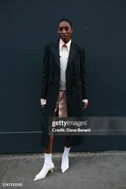 Sophia Brown poses wearing a pink dress, white jumper, striped trench coat, black bag and white shoes & socks outside the S.S.Daley show during...