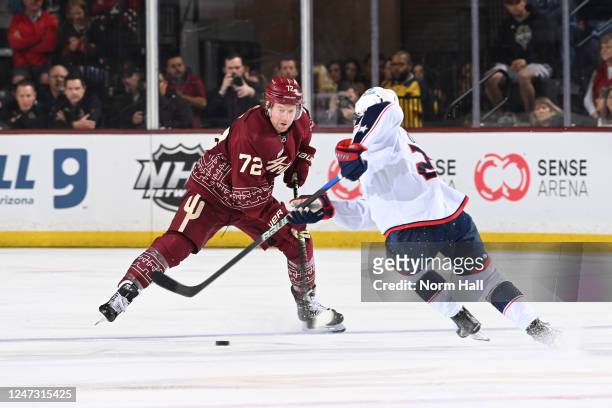 Adam Boqvist of the Columbus Blue Jackets skates with the puck while being defended by Travis Boyd of the Arizona Coyotes during the third period at...