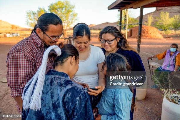 navajo familie tijd besteden aan het delen van foto's vanaf een smartphone - navajo etniciteit stockfoto's en -beelden