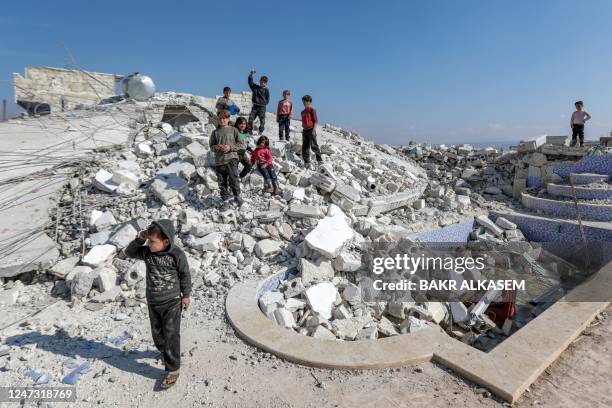Children stand on the rubble of a collapsed building in the aftermath of the February 6 deadly earthquake that hit Syria and Turkey, in Jindayris in...