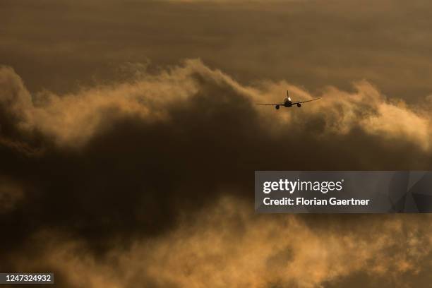 An airplane is pictured in as silhouette in front of the evening light near the BER airport on February 19, 2023 in Berlin, Germany.