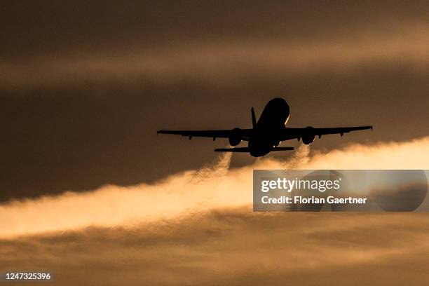An airplane is pictured in as silhouette in front of the evening light near the BER airport on February 19, 2023 in Berlin, Germany.
