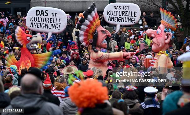 Revellers celebrate around a float featuring a parrot pointing on a native American Indian who in turn points on a carnival fool dressed as an...