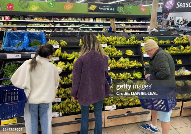 Customers shop for bananas in the fruit and vegetable section of a Sainsbury's supermarket in east London on February 20, 2023. - British retail...