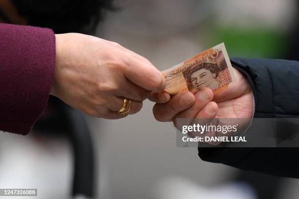 Customer uses a ten pound note to pay for goods at a market in east London on February 20, 2023. British retail sales rebounded surprisingly in...