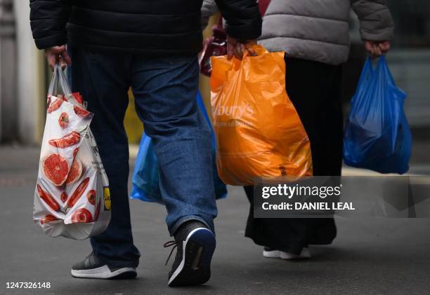Shoppers carry their purchases in Aldi and Sainsbury's plastic shopping bags, in east London on February 20, 2023. British retail sales rebounded...